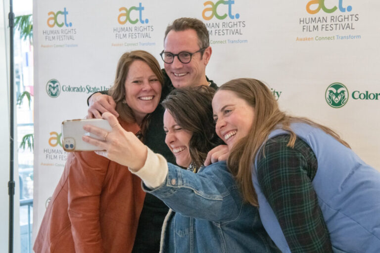 Group of four people take a photo in front of Act Human Rights Film Festival background